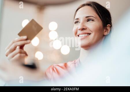 Femme professionnelle regardant loin en payant par carte de crédit à café-restaurant Banque D'Images