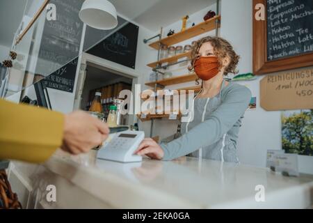 Paiement mobile effectué par une femme dans un magasin de déchets zéro client en cas de pandémie Banque D'Images