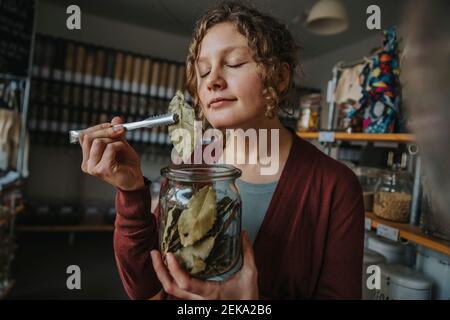 Femme employée avec les yeux fermés odeur feuille de baie pendant le travail dans un magasin sans déchets Banque D'Images