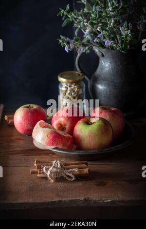 Pommes fraîches dans une assiette avec bâtonnets de cannelle sur fond de bois naturel. Banque D'Images