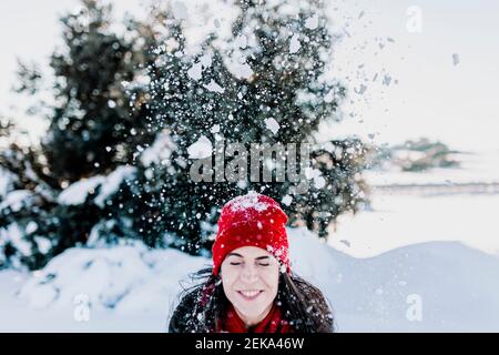 Neige tombant sur une femme souriante en vacances à la campagne Banque D'Images