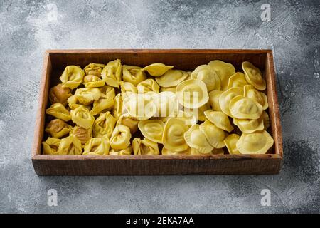 Tortellini et Ravioli faits main à l'italienne, en boîte de bois, sur fond gris Banque D'Images