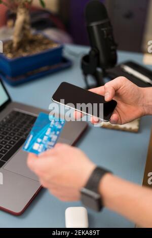 Homme d'affaires avec carte de crédit faisant des achats par téléphone mobile à accueil Banque D'Images