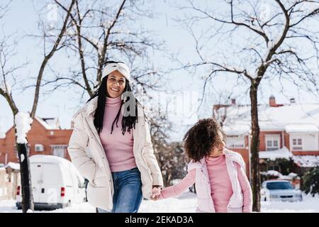 Mère et fille tenant les mains tout en marchant dans la rue pendant hiver Banque D'Images