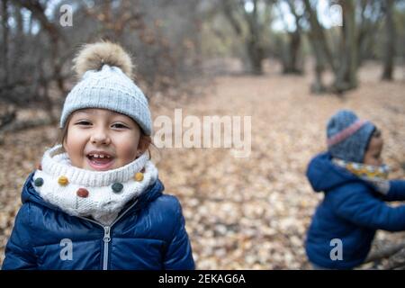 Mignon garçon portant des vêtements chauds qui regardent loin en forêt pendant l'automne Banque D'Images