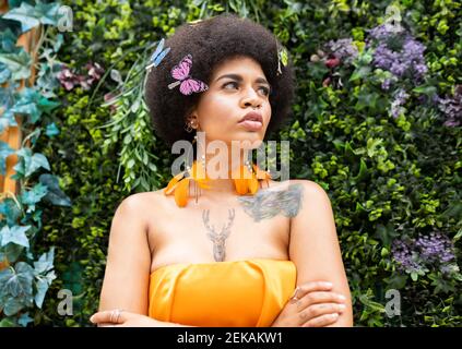 Femme afro regardant loin contre les plantes Banque D'Images