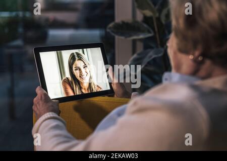 Femme âgée en conversation vidéo avec sa petite-fille via une tablette numérique à la maison Banque D'Images