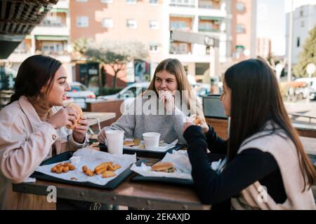 Des amies qui ont un fast-food au restaurant en plein air Banque D'Images