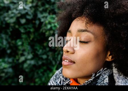 Jeune femme afro avec les yeux fermés à la lumière du soleil