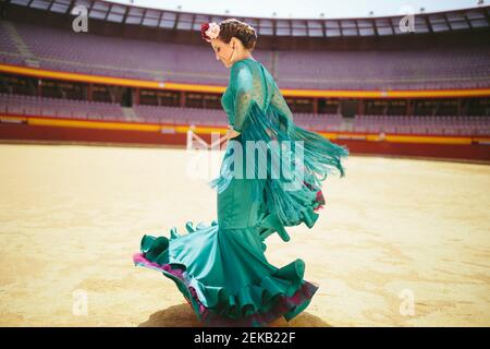 Jeune femme vêtue d'une robe bleue dansant du flamenco dans un arène Banque D'Images