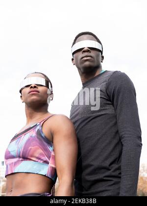 Sportsman et sportswoman dans des lunettes de soleil regardant loin contre le ciel clair Banque D'Images