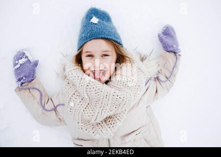 Fille gaie qui colle la langue sur la neige pendant les vacances Banque D'Images