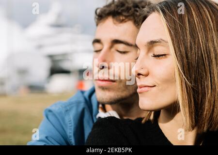 Jeune couple avec les yeux fermés à l'extérieur Banque D'Images