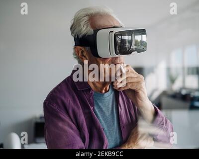 Homme d'affaires attentionné avec des chi à main grâce à un casque de réalité virtuelle au bureau Banque D'Images