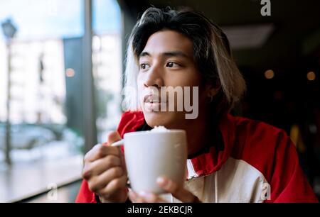 Jeune homme ayant un café dans un café pendant l'hiver Banque D'Images