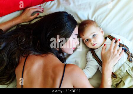 Une jeune femme se reposant avec un bébé garçon tout en étant couché sur le lit Banque D'Images