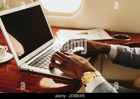 Les hommes d'affaires tapant les mains sur un ordinateur portable dans un jet privé Banque D'Images