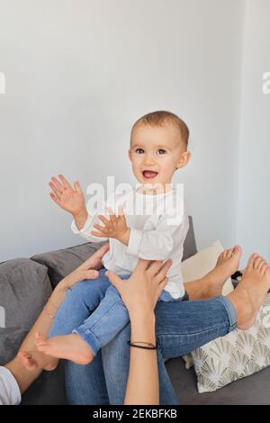 Bébé fille riant en jouant avec la mère sur le canapé Banque D'Images