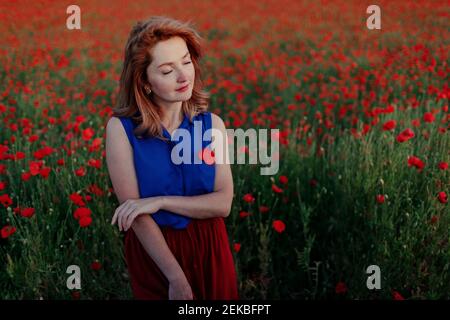 Belle femme avec les yeux fermés dans le champ de pavot Banque D'Images