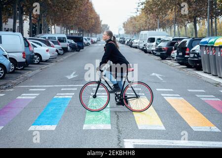 Femme en vélo sur le zébra multicolore croisant Banque D'Images