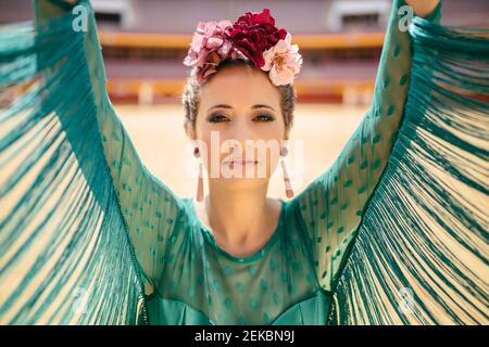 Gros plan de la belle femme portant une robe bleue et des fleurs avec les bras levés dansent dans les arènes Banque D'Images