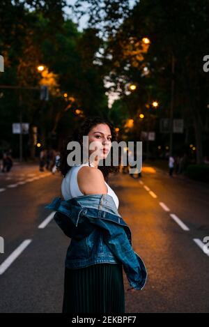 Belle femme portant une veste en denim debout dans la rue coucher de soleil Banque D'Images