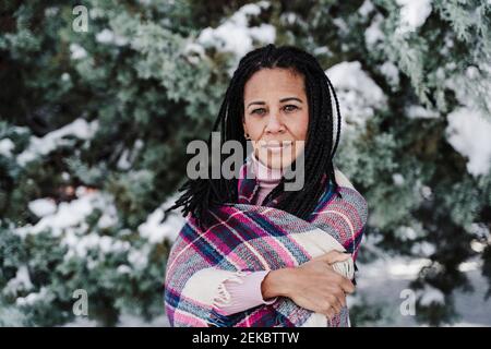 Femme mûre avec les bras croisés enveloppés dans le châle à plaid stationnement Banque D'Images