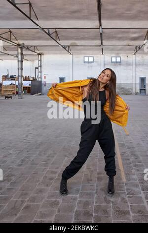 Danseuse moderne en veste jaune à l'usine abandonnée Banque D'Images