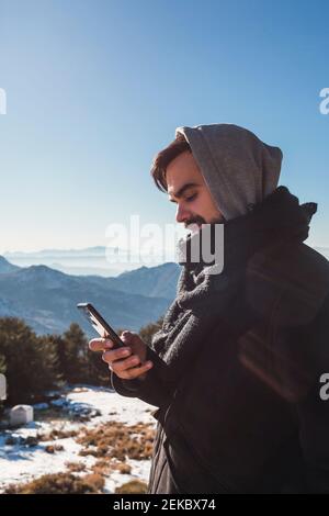 Portrait d'un homme envoyant un message avec son smartphone dans la neige Banque D'Images