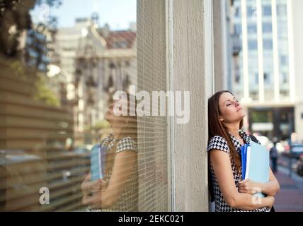 Jeune femme d'affaires exténuée, les yeux fermés, penchée sur le mur Banque D'Images