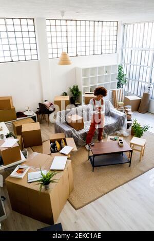 Femme afro écrivant dans le bloc-notes tout en se tenant dans un nouveau loft appartement Banque D'Images