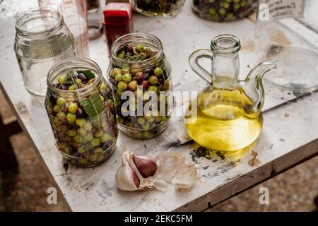 Pots en verre remplis d'olives et d'ail conservés sur la table Banque D'Images