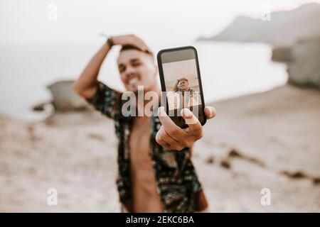 Jeune homme prenant le selfie par téléphone intelligent à Almeria, désert de Tabernas, Espagne Banque D'Images
