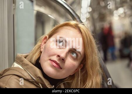 Jeune femme blanche examine la carte du métro à l'intérieur du chariot de métro. Banque D'Images