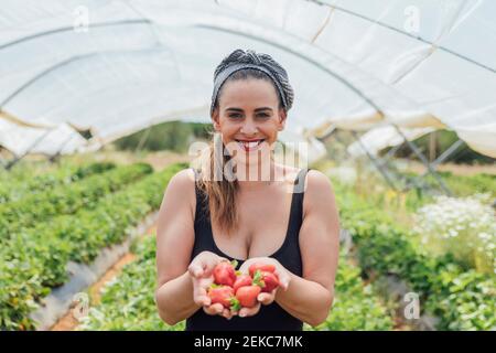 Bonne belle paysanne féminine tenant des fraises fraîches à la ferme biologique Banque D'Images