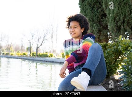 Une jeune fille attentionnés se détendant sur le mur de soutènement au parc Banque D'Images