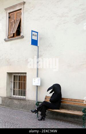 Femme en costume d'oiseau assise sur le banc de l'arrêt de bus Banque D'Images