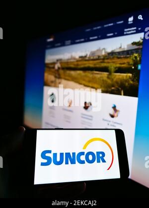 Personne qui détient un smartphone avec le logo de la société énergétique canadienne Suncor énergie Inc. À l'écran devant le site Web. Mise au point sur l'affichage du téléphone. Banque D'Images