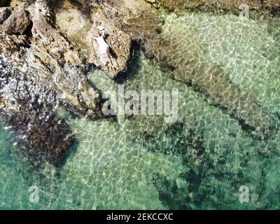 Vue aérienne d'une femme mûre sur le rocher à la plage par beau temps Banque D'Images