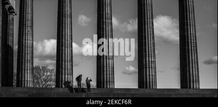 Couple solitaire sur les marches du monument national écossais sur Calton Hill, Édimbourg lors d'une journée ensoleillée pendant l'enfermement 2021. Prise de vue en noir et blanc spectaculaire Banque D'Images