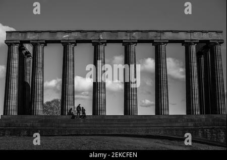 Couple solitaire sur les marches du monument national écossais sur Calton Hill, Édimbourg lors d'une journée ensoleillée pendant l'enfermement 2021. Prise de vue en noir et blanc spectaculaire Banque D'Images