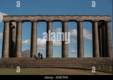 Couple solitaire sur les marches du monument national écossais sur Calton Hill, Édimbourg lors d'une journée ensoleillée pendant l'enfermement 2021 Banque D'Images