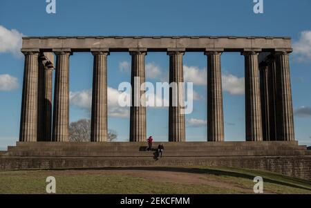 Couple solitaire sur les marches du monument national écossais sur Calton Hill, Édimbourg lors d'une journée ensoleillée pendant l'enfermement 2021 Banque D'Images