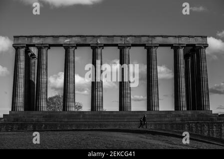 Couple solitaire sur les marches du monument national écossais sur Calton Hill, Édimbourg lors d'une journée ensoleillée pendant l'enfermement 2021. Prise de vue en noir et blanc spectaculaire Banque D'Images