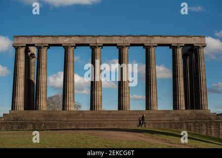Couple solitaire sur les marches du monument national écossais sur Calton Hill, Édimbourg lors d'une journée ensoleillée pendant l'enfermement 2021 Banque D'Images