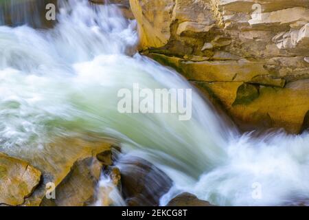 Vue aérienne de la cascade de la rivière avec de l'eau turquoise claire tombant entre des blocs mouillés avec de la mousse blanche épaisse. Banque D'Images