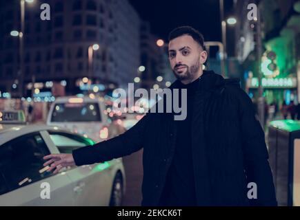 Beau jeune homme qui se hante en taxi dans la ville la nuit Banque D'Images