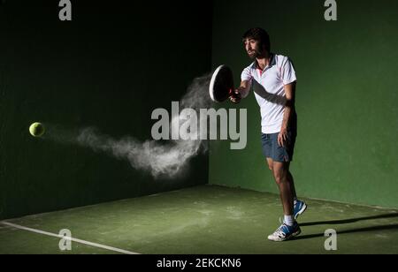 Un athlète masculin s'est fait servir le ballon tout en jouant au padel tennis sur un terrain de sport la nuit Banque D'Images