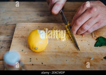 Gros plan du chef coupant le zeste de citron sur la planche à découper cuisine Banque D'Images