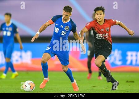 Le joueur brésilien de football Olivio da Rosa, également connu sous le nom d'Ivo, de Henan Jianye F.C., à gauche, protège le ballon lors du quatrième tour de la Super League chinoise (CSL) 2020 contre Shenzhen F.C., Dalian ville, province de Liaoning au nord-est de la Chine, 10 août 2020. Le F.C. Shenzhen a été battu par le F.C. Henan Jianye avec 1-2.